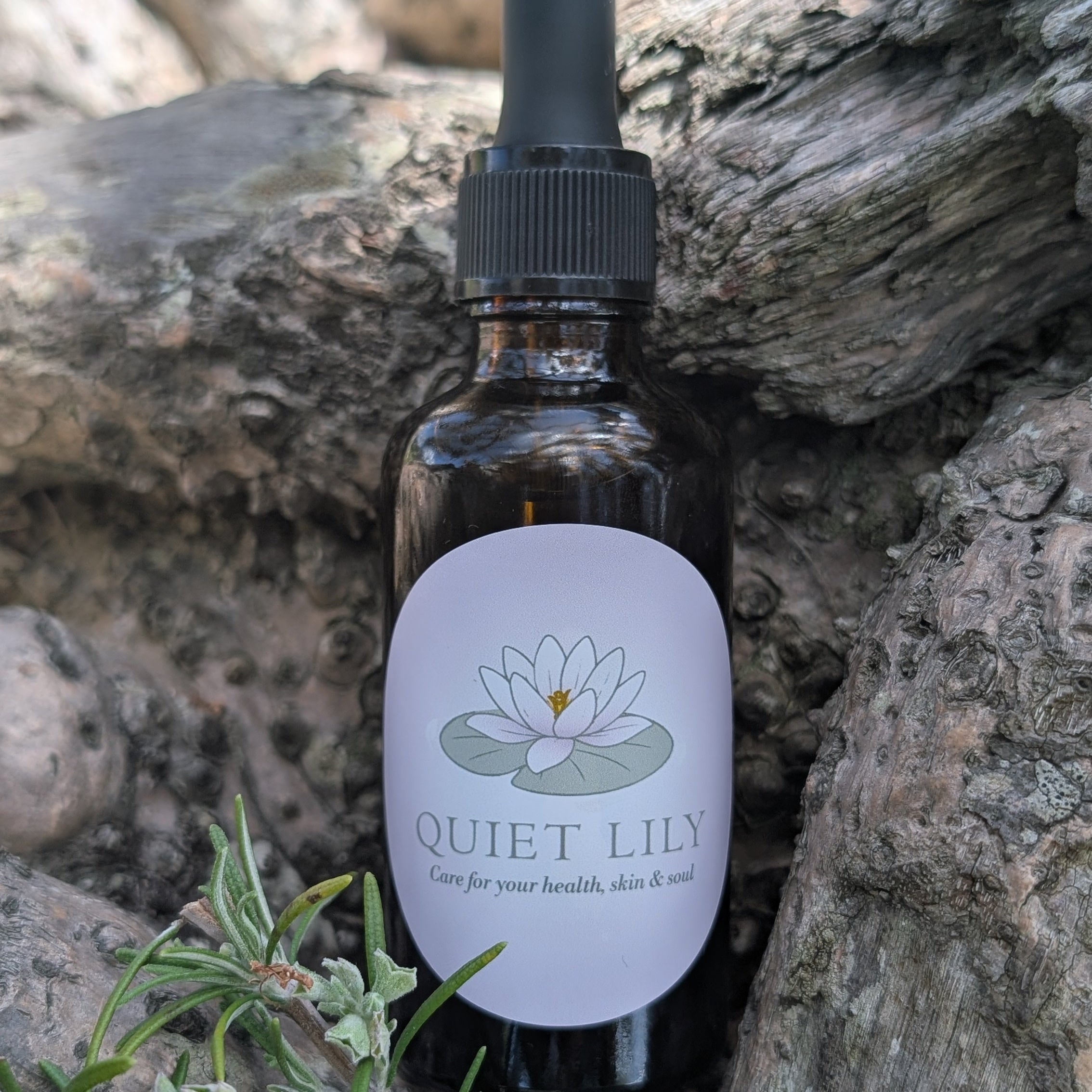 Bottle of 'Quiet Lily' product with a dropper on a stone background