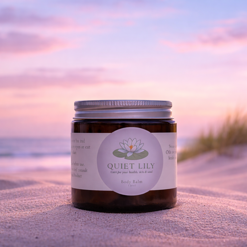 Jar of 'Quiet Lily' product on a sandy beach with a sunset in the background