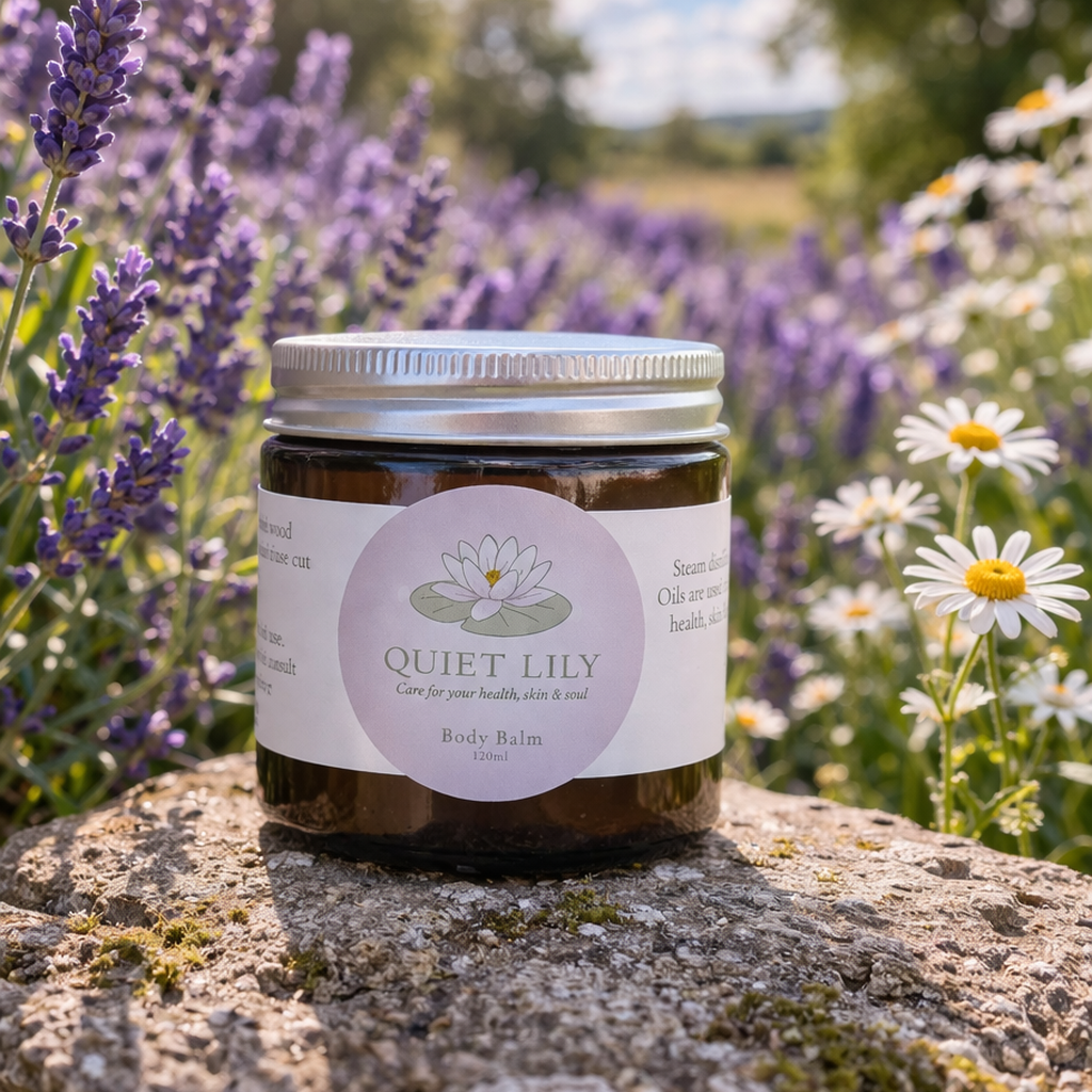 Jar of 'Quiet Lily' balm on a stone surface with lavender and daisies in the background