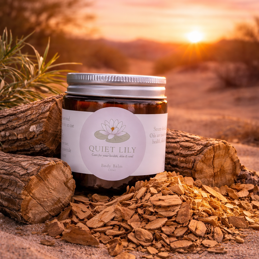 Jar of 'Quiet Lily' product on a log with a desert sunset background